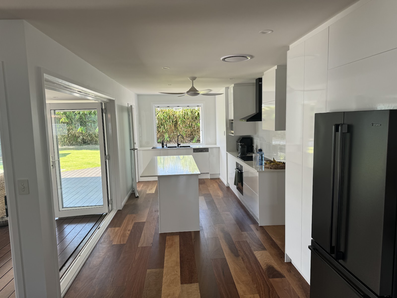 Finished white kitchen with a long island bench and timber floorboards