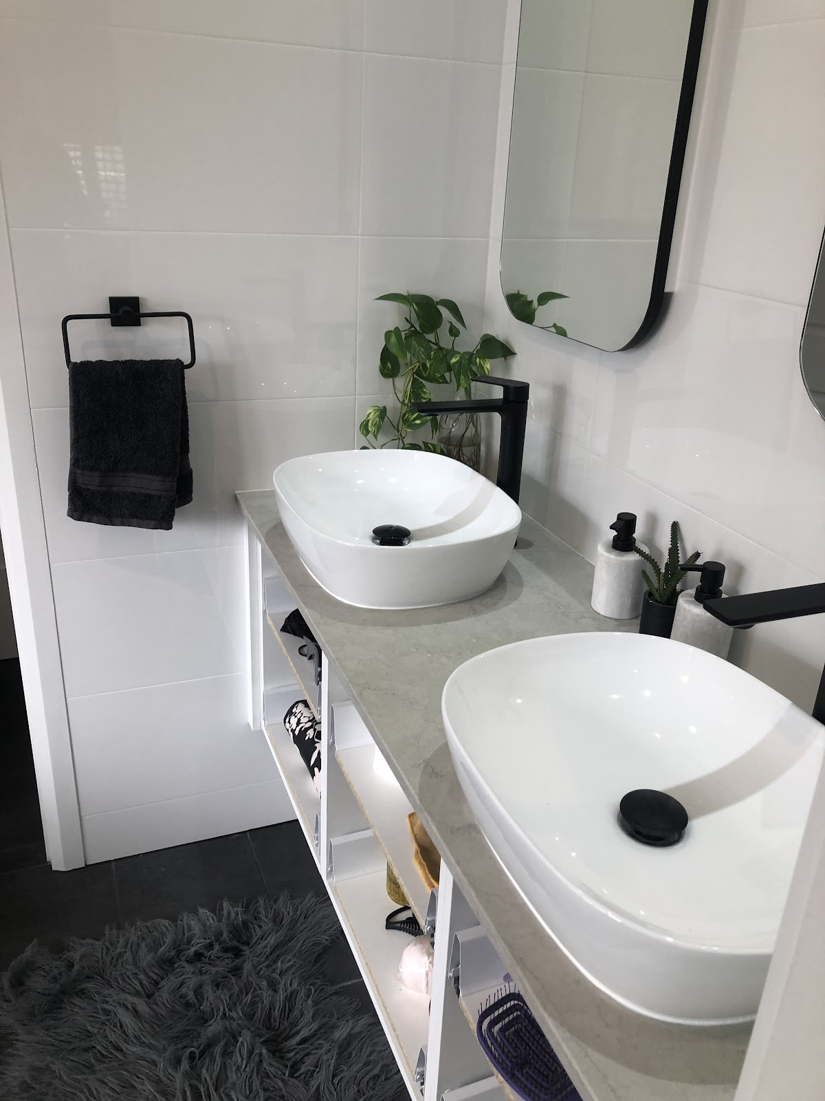 Double vessel basins on a stone top with open shelving and black tapware