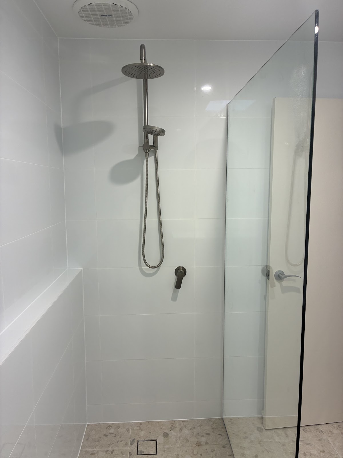 Shower with a tiled ledge and brushed nickel fittings