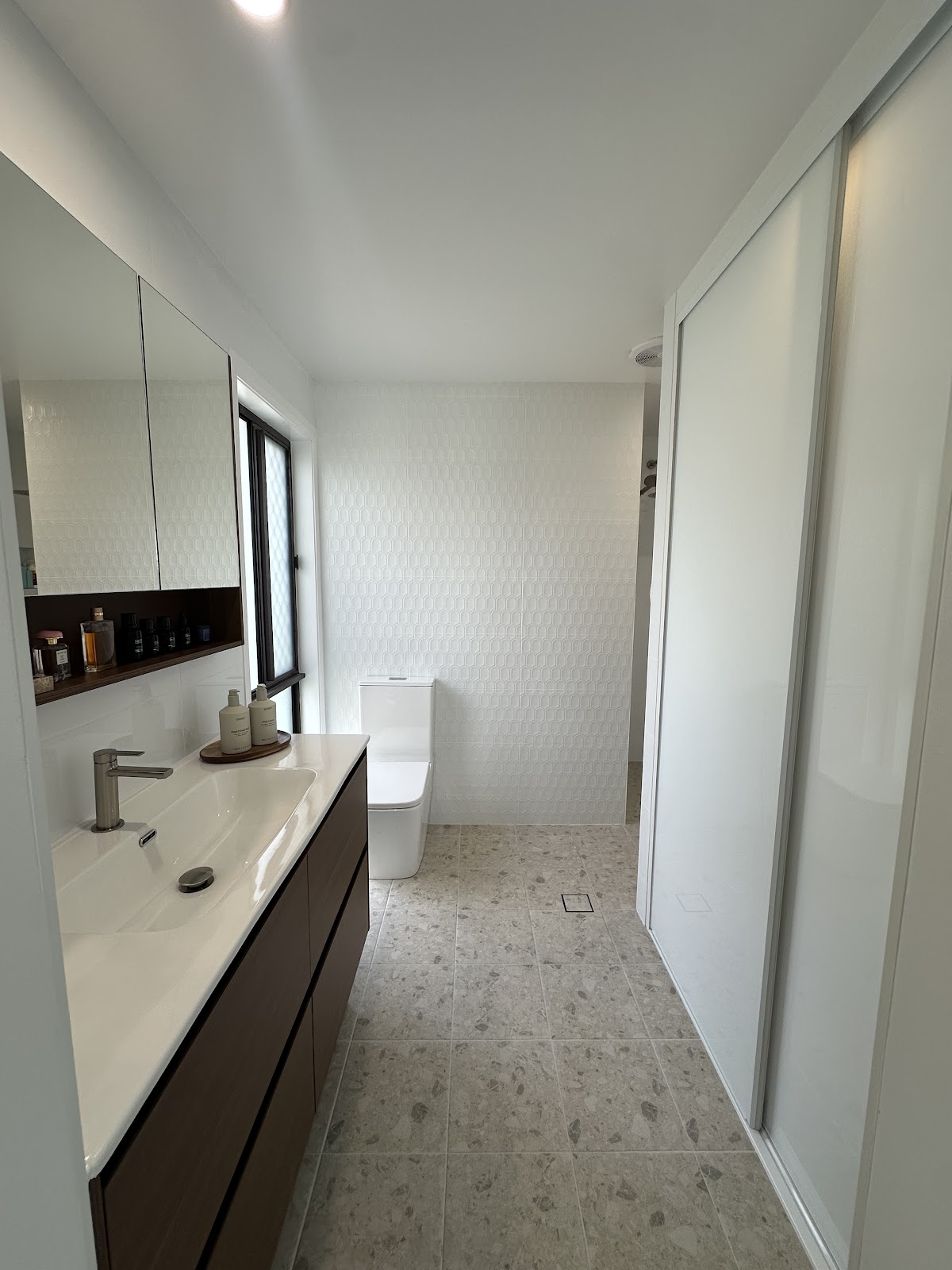 Long vanity with a timber cabinet beside a built-in wardrobe